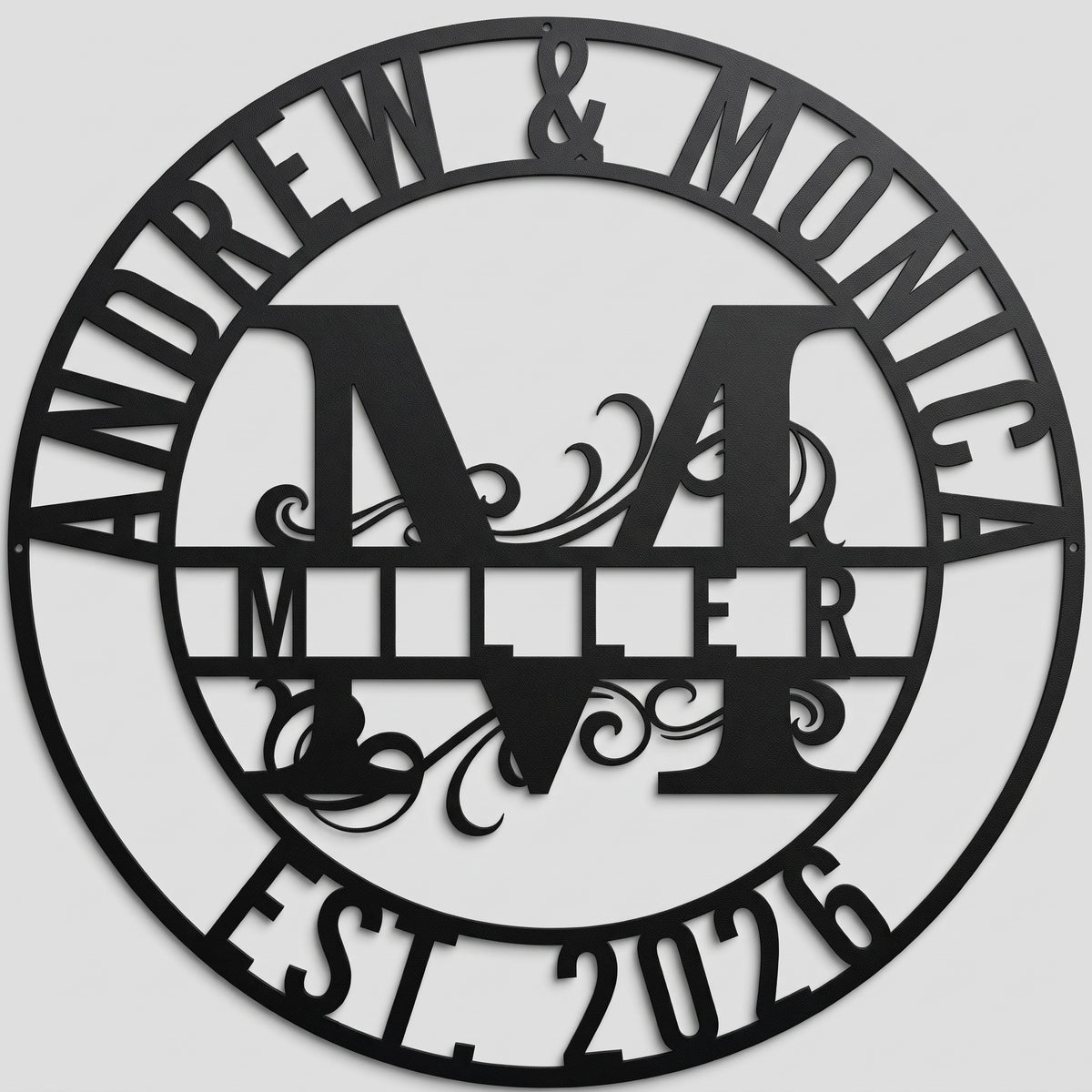 Personalized Monogram Family Name custom metal sign in matte black finish featuring a central initial, couple names, and established year, mounted straight-on against a neutral gray studio wall.